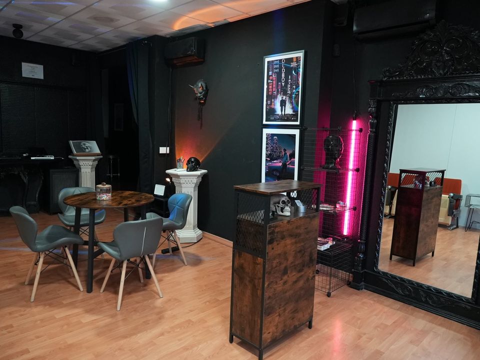 Interior del estudio con el póster de Oldboy, un neón rosa, una calavera y un gran espejo con marco tallado