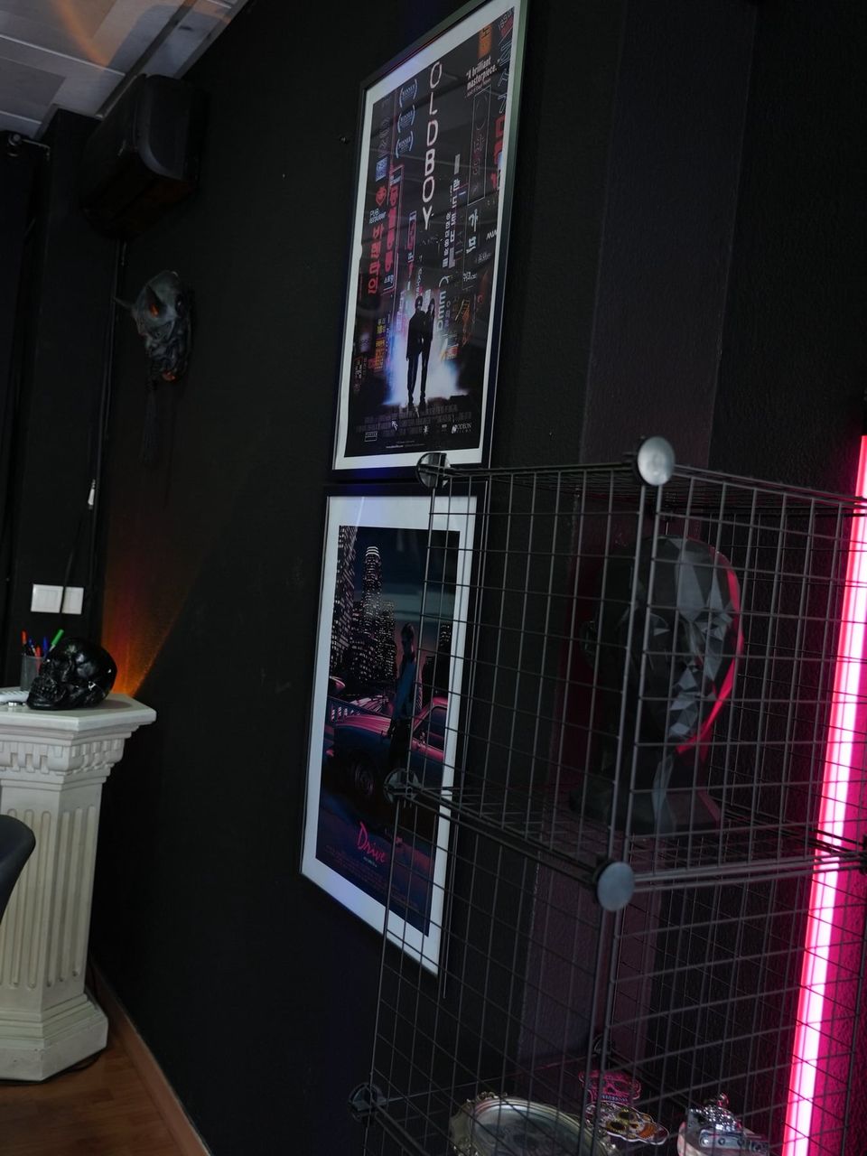 Pósters de las películas Oldboy y Drive junto a una luz de neón rosa