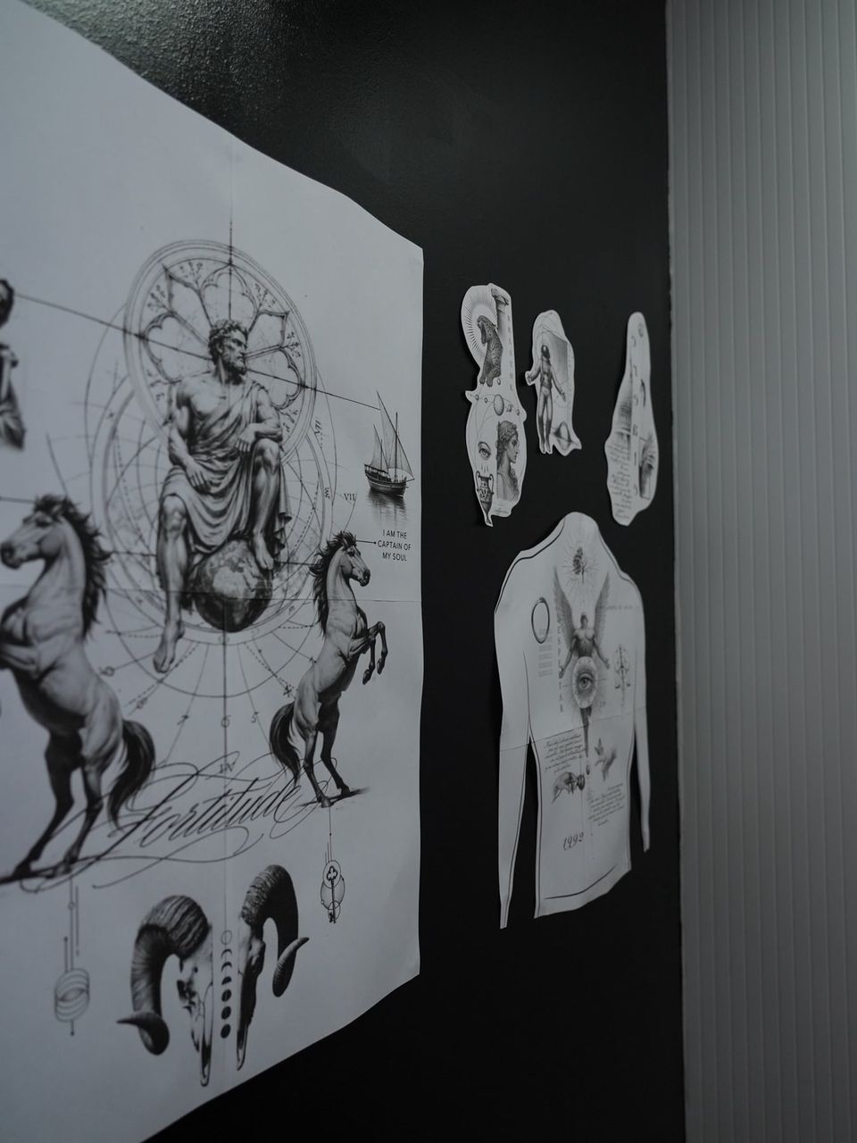 Diseños de tatuajes conceptuales colgados en la pared: una figura clásica sobre una esfera rodeada de caballos, geometría y la palabra «Fortitude»