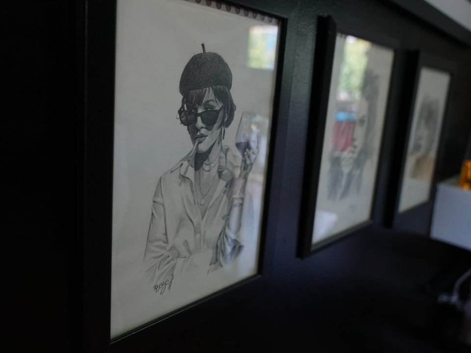 Dibujos a lápiz enmarcados de Jose Alvarez: retrato de una mujer con boina, gafas de sol y una copa de vino