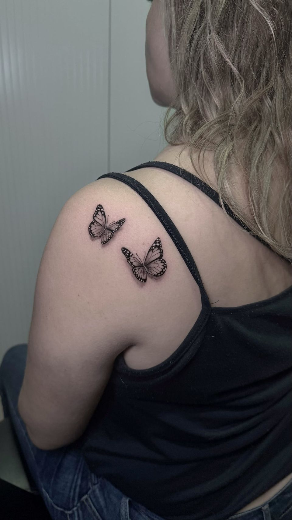 Tatuaje de línea fina con sombreado realista en el hombro: dos mariposas monarca en negro y grises